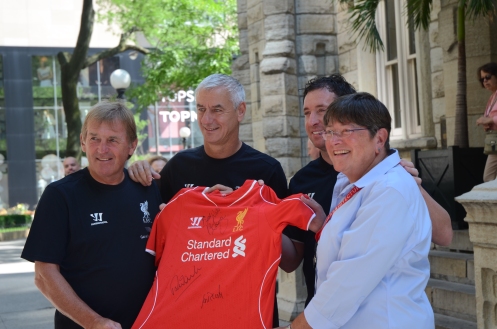 Chicago Architecture Foundation representative receives a signed team jersey from Kenny Dalglish, Ian Rush and Robbie Fowler in front of the Water Tower in Chicago, Summer 2014.